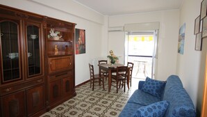 A dining area with a wooden cabinet, a dining table with chairs, and a patterned floor. - Casa Lungomare (Cefalù)