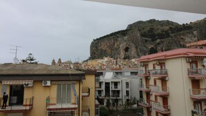 A residential area with multi-story buildings, balconies, and a mountainous backdrop. - Casa Lungomare (Cefalù)