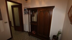 A hallway with patterned carpet, a wooden cabinet, and a radiator. - Casa Lungomare (Cefalù)