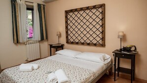 Una camera da letto con un letto, due comodini, una lampada a parete e una finestra con tende.