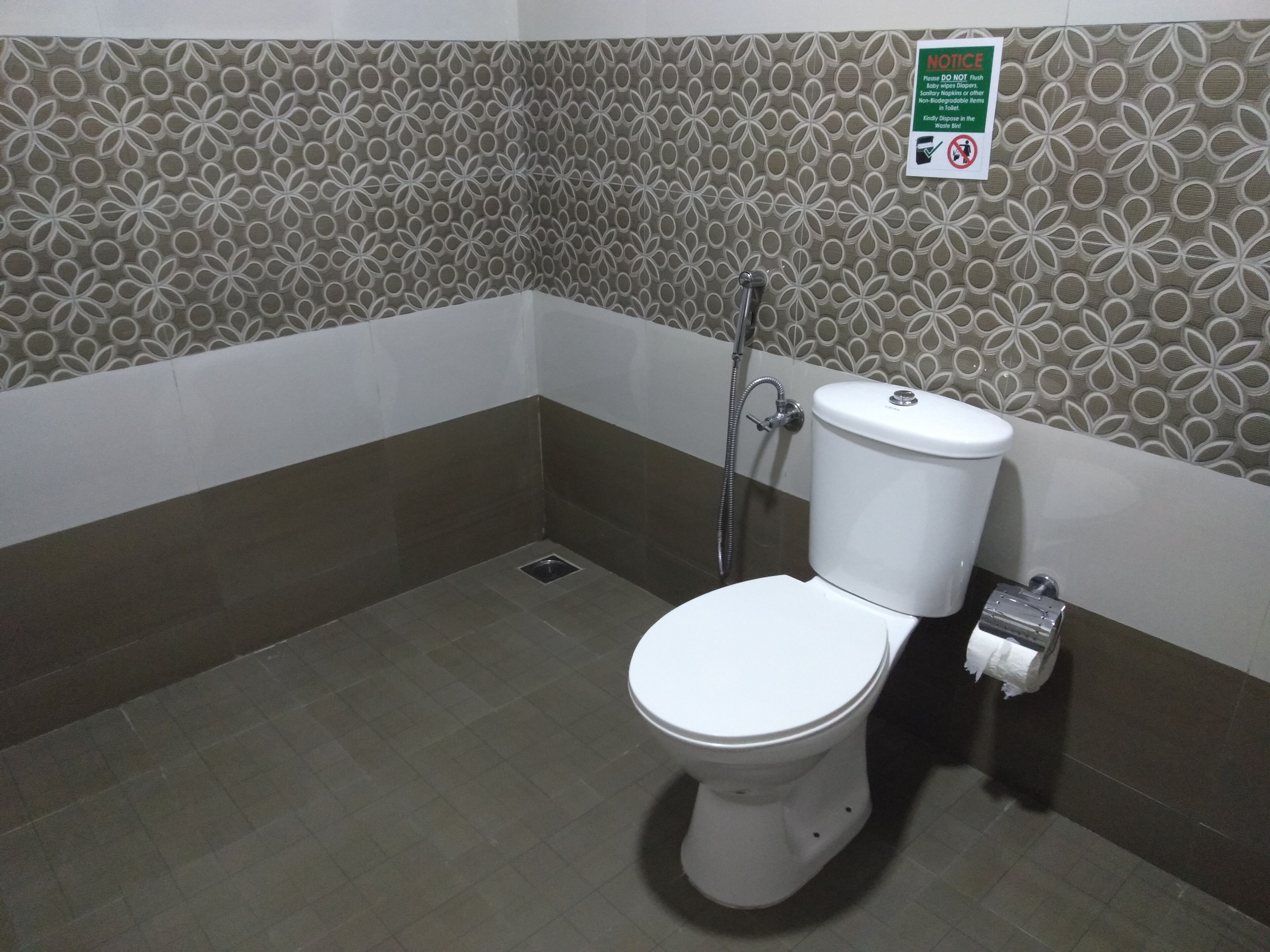 A bathroom with a toilet, a shower, and a waste bin.