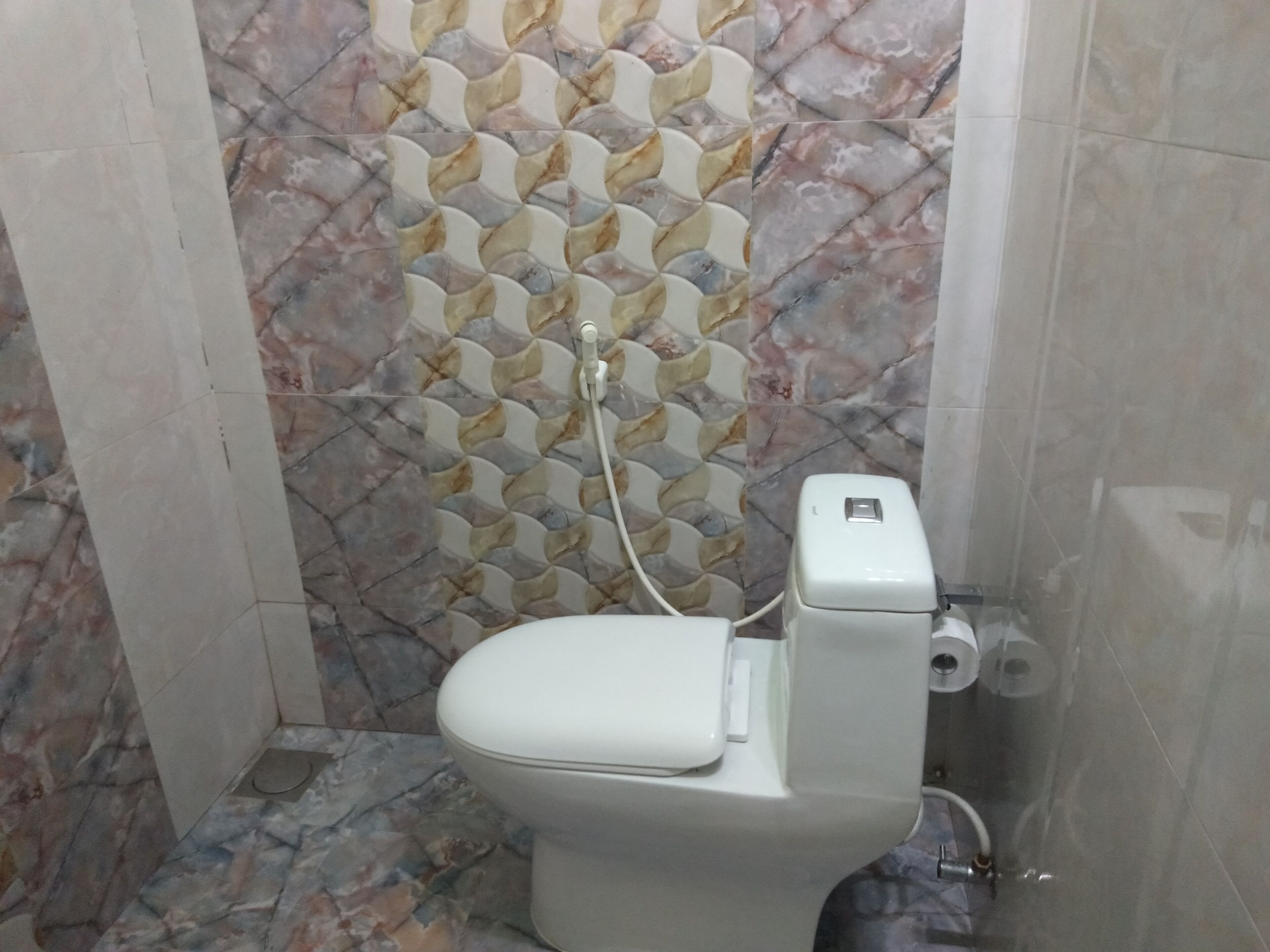 Un baño con inodoro, un bidé empotrado y un salpicadero con diseño de mármol.
