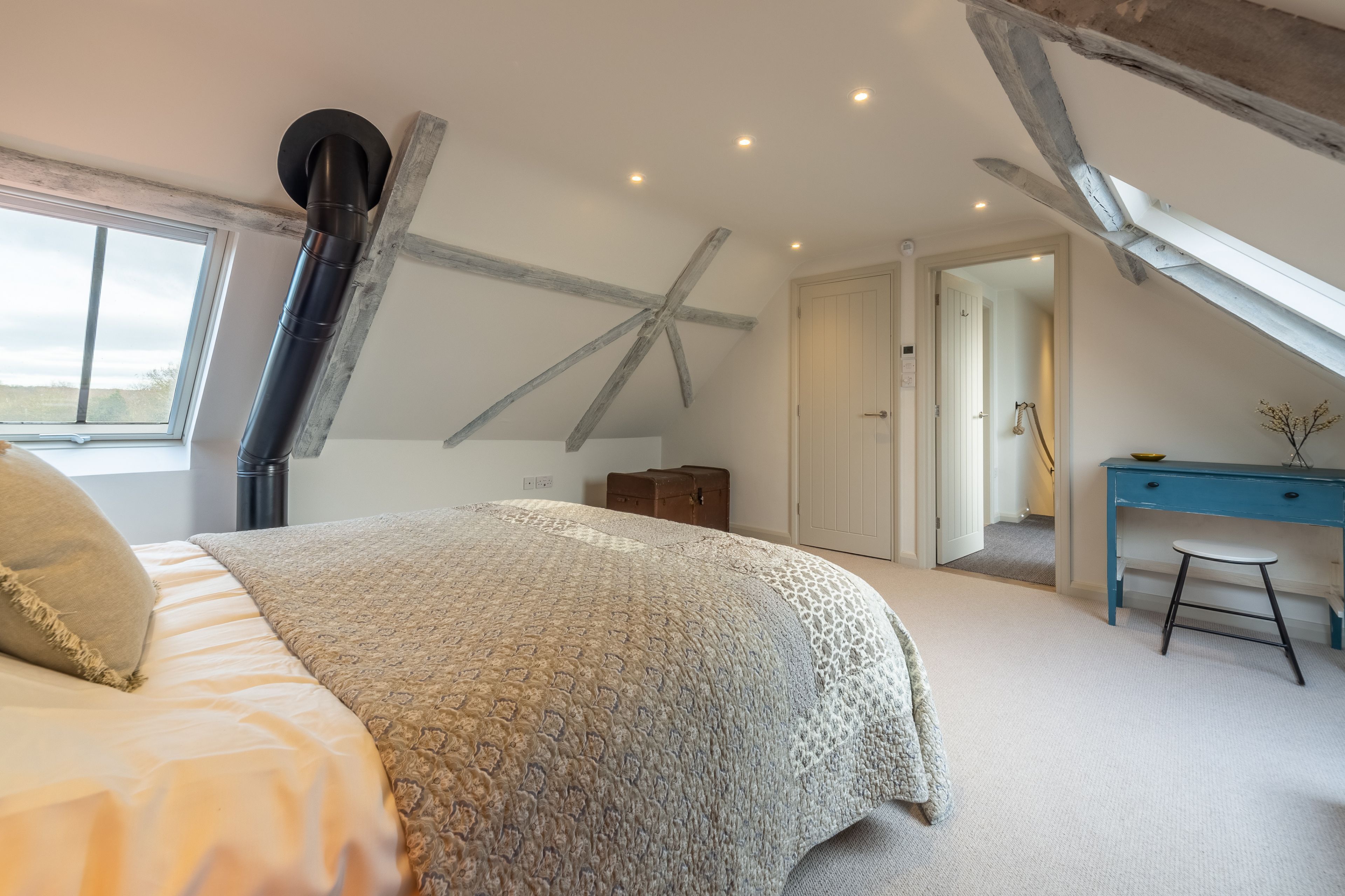 A bedroom with a large bed, a desk, and a window.