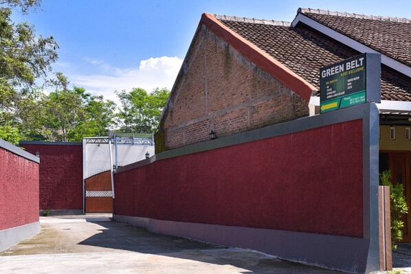 A red brick building with a green belt sign indicating a cost exclusive area. - Green Belt Kost Exclusive (Ngemplak)