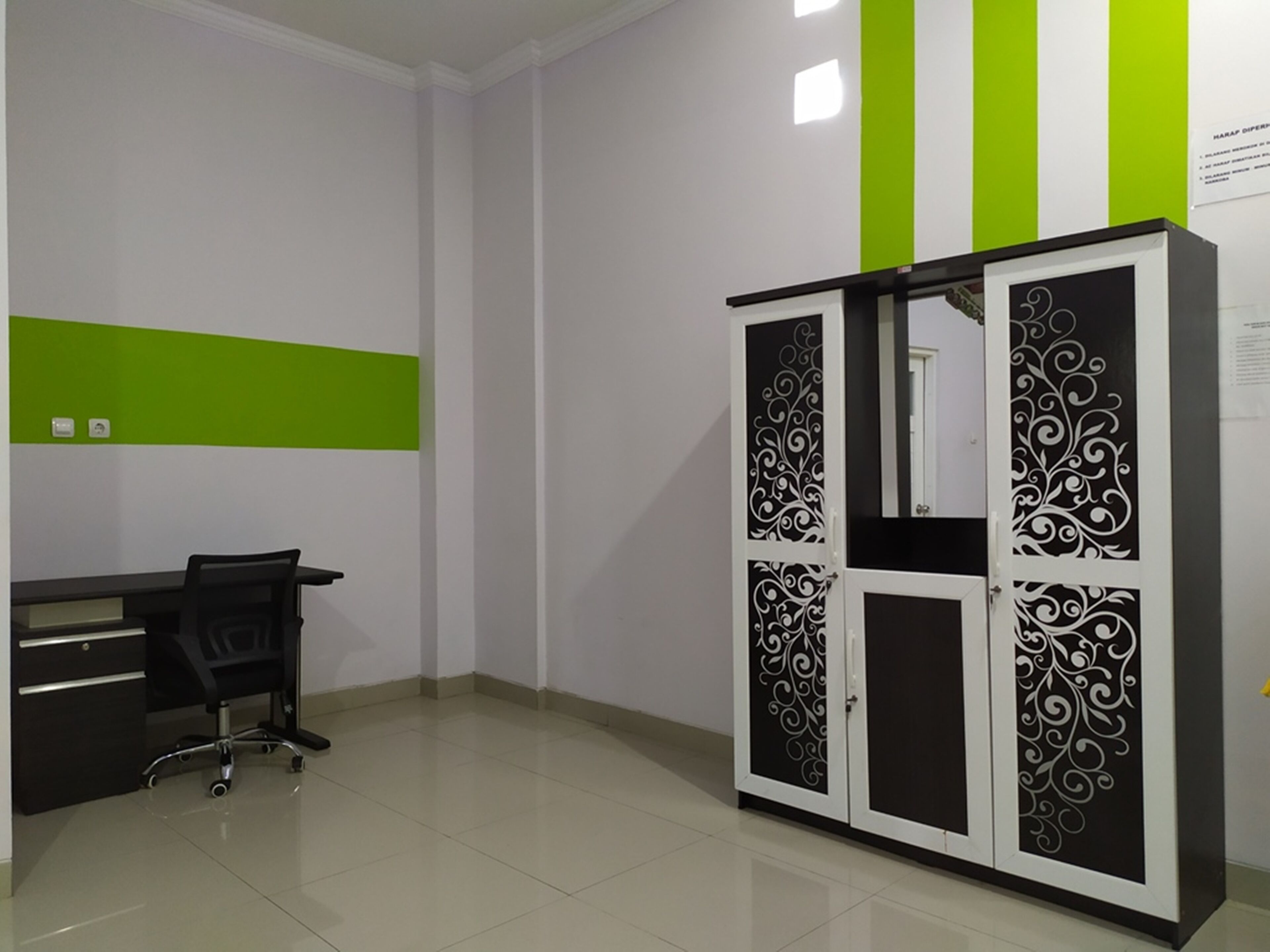 A room with a desk, chair, and a wardrobe with decorative panels.