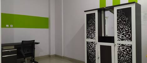 A room with a desk, chair, and a wardrobe with decorative panels.
