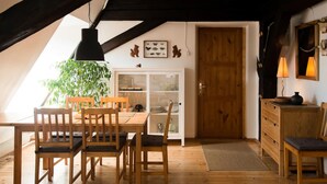 A cozy dining area with wooden furniture, a glass cabinet, and a wooden door. - Sunny mansard in the heart of Old Town (Centra rajons)
