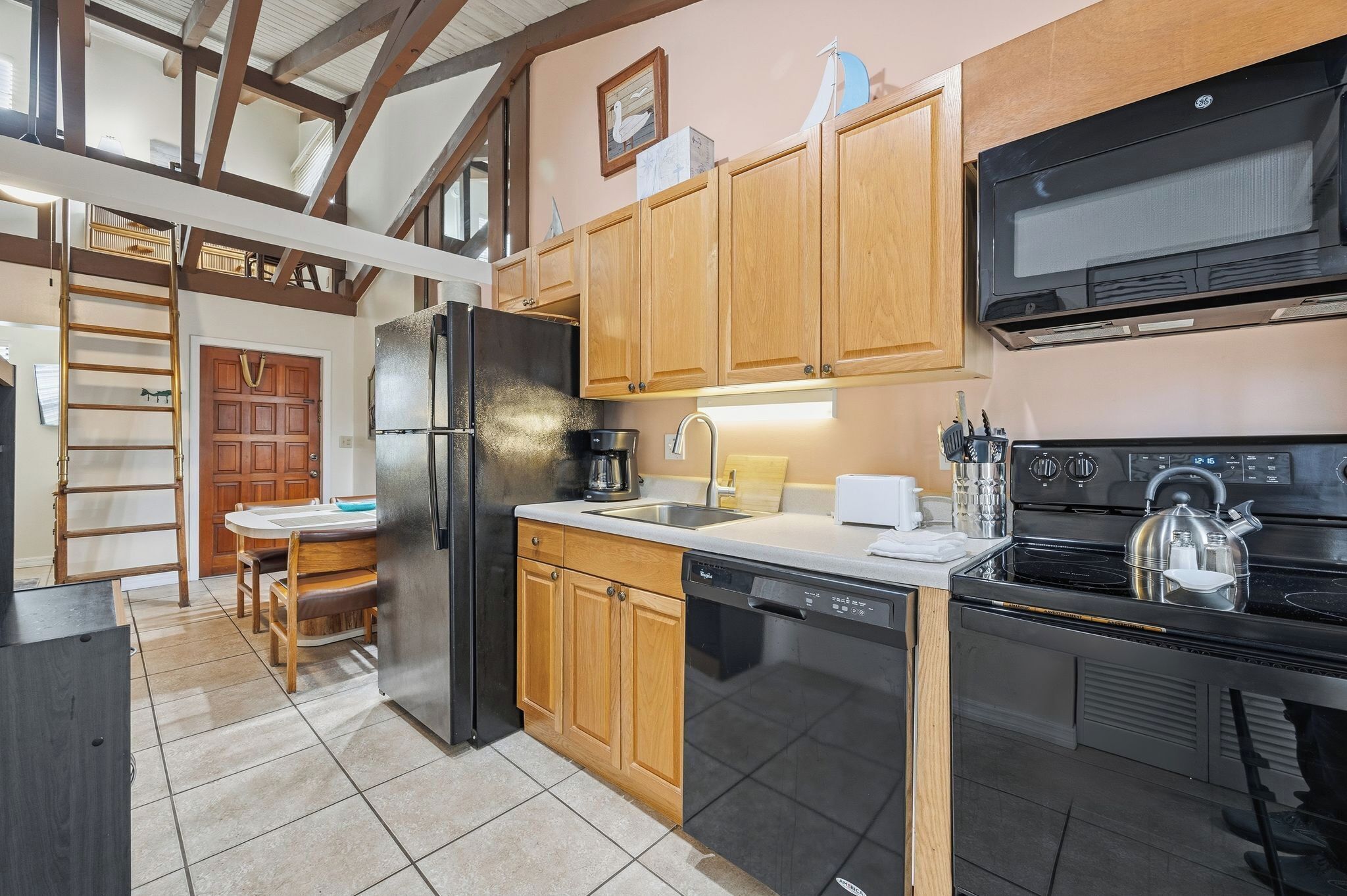 Una cucina con mobili in legno, frigorifero in acciaio inossidabile, lavastoviglie, piano cottura e forno a microonde.