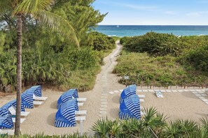 A beach path leading to beach chairs with umbrellas, surrounded by greenery and overlooking the ocean. - Sand Dune Shores (Singer Island)