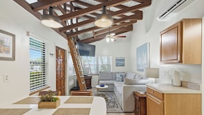 A spacious living area with a dining table, sofa, and kitchen cabinetry.