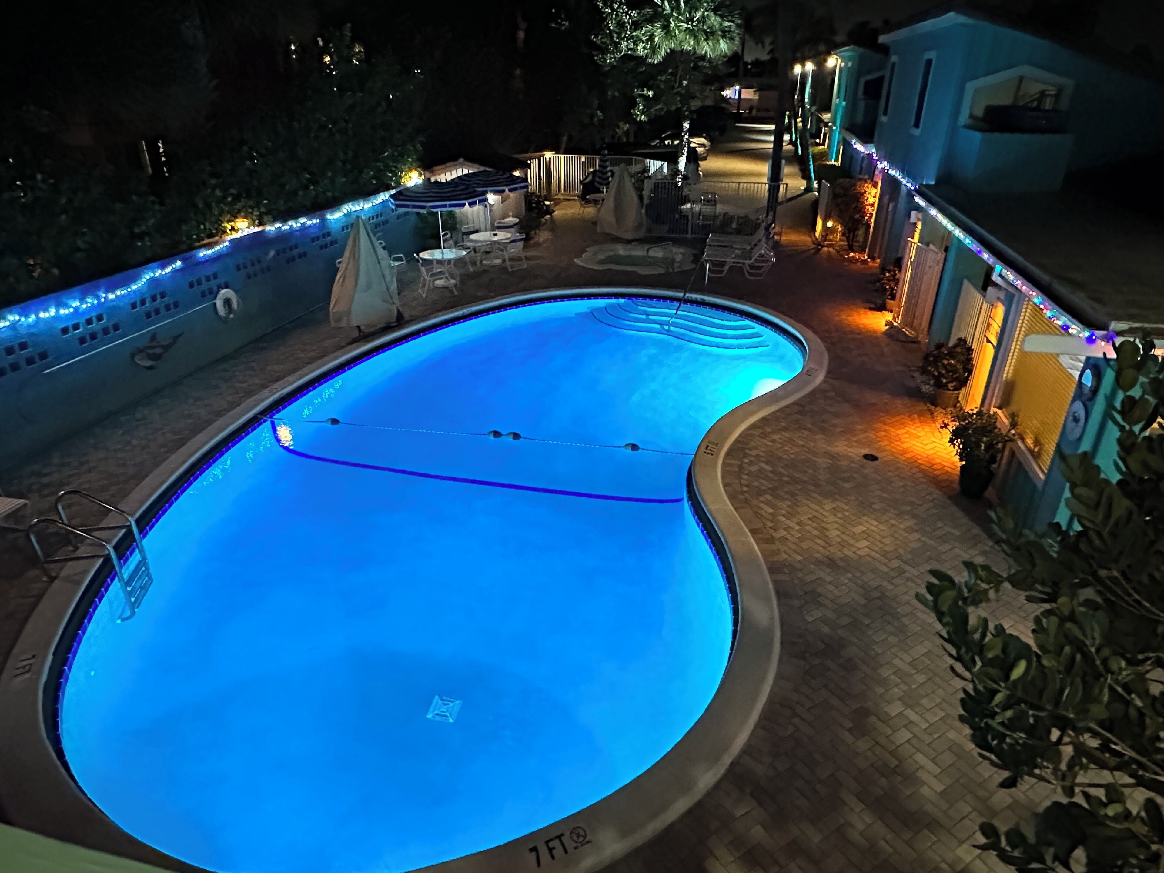 A swimming pool with a curved design, surrounded by outdoor seating and potted plants.