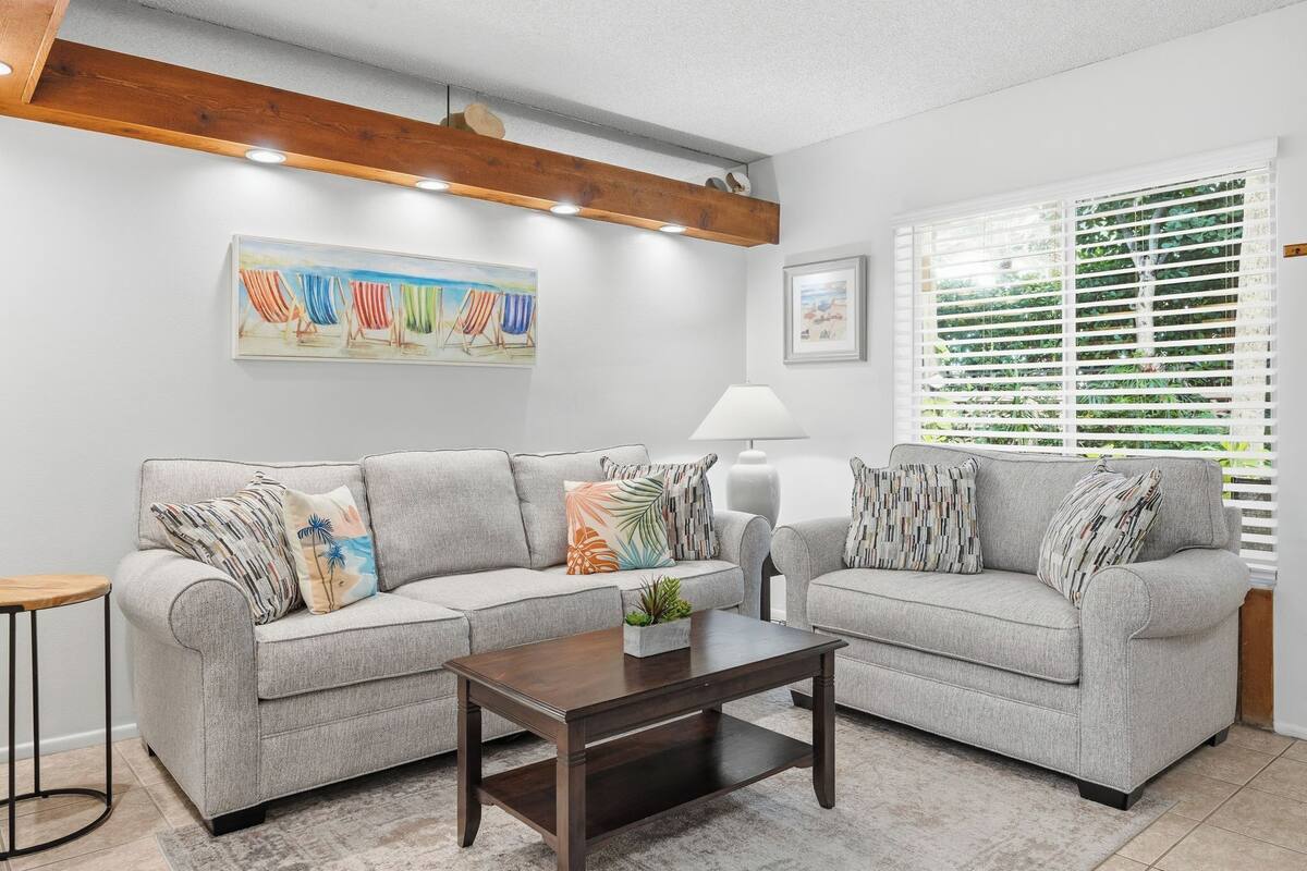 A living room with two grey sofas, a wooden coffee table, a small plant, and a painting on the wall.