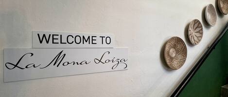 A welcome sign with "WELCOME TO La Mona Loiza" on a wall.