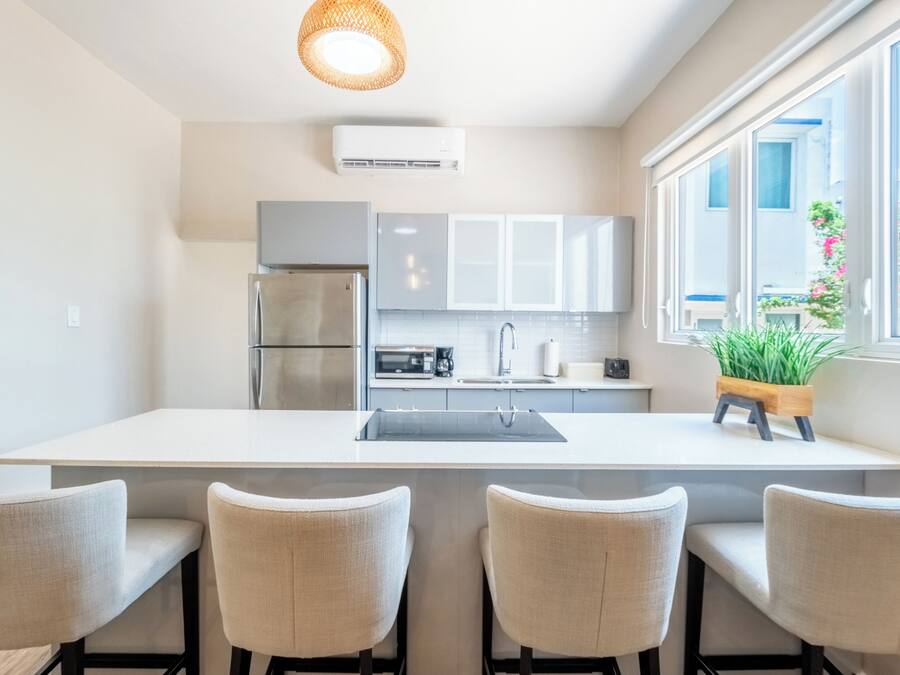 A modern kitchen with a central island, stainless steel appliances, and a large window with a view of greenery.