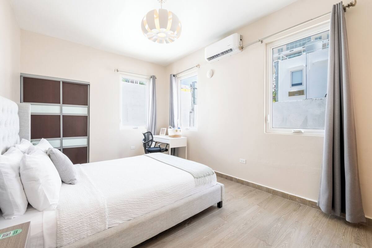 A hotel room with a bed, a desk, and a window.