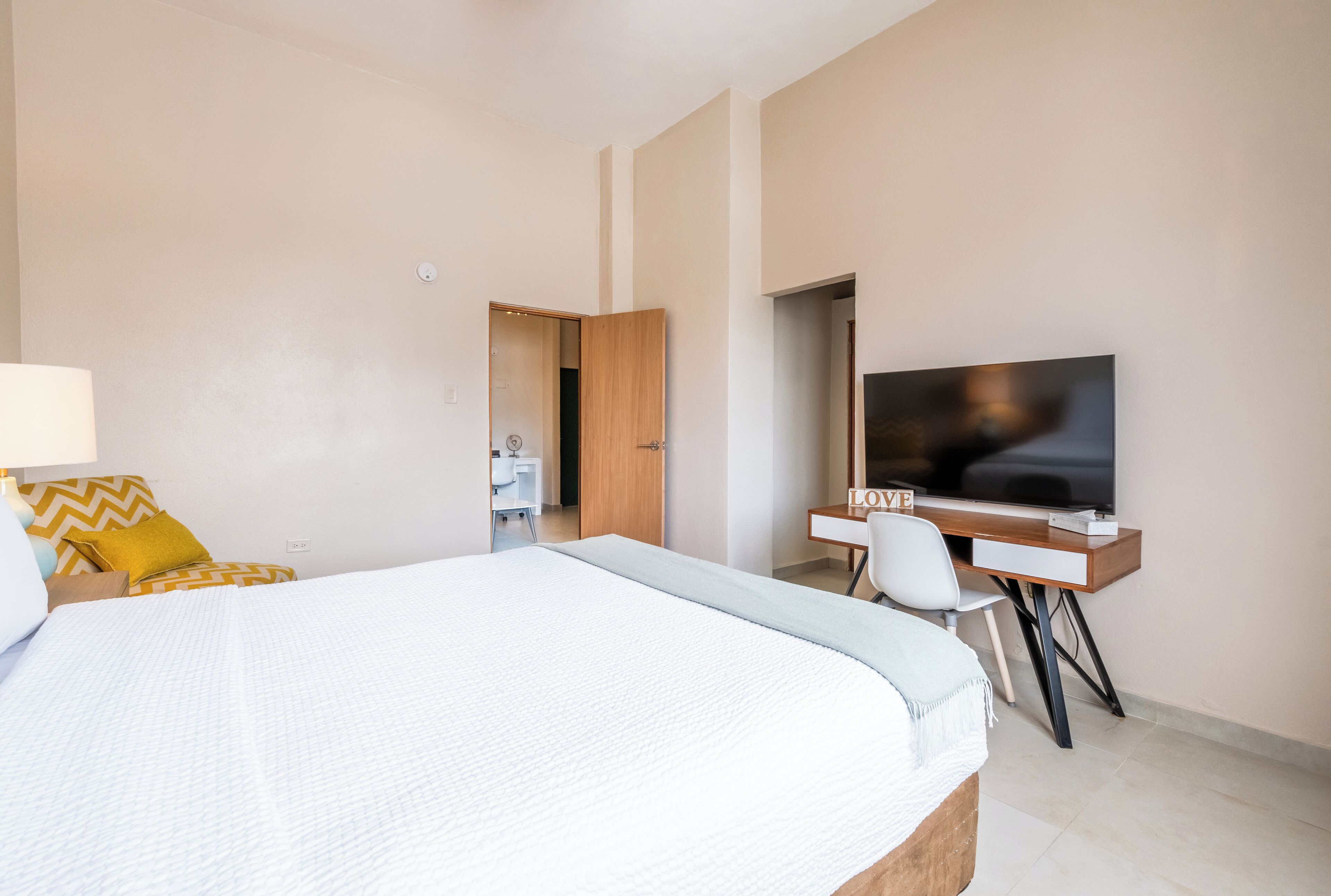 Een hotelkamer met een groot bed, een bureau met een televisie en een badkamer zichtbaar door een geopende deur.