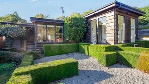 A modern house with a well-maintained garden, featuring neatly trimmed hedges and a gravel pathway. - Sophisticated Artist's Retreat (Stinson Beach)