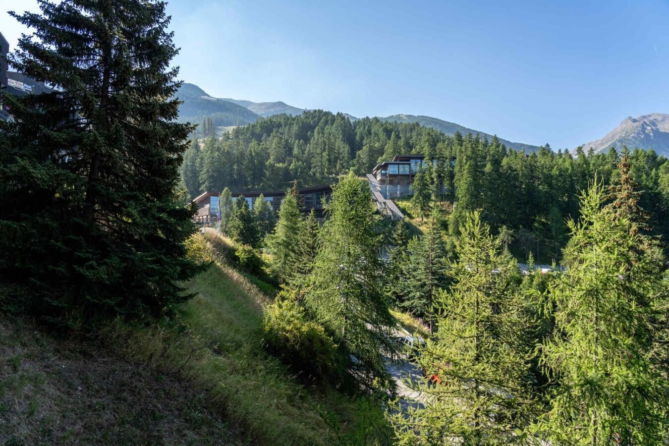 Ein modernes Gebäude, eingebettet in eine bewaldete Gegend mit freiem Blick auf die umliegenden Berge.