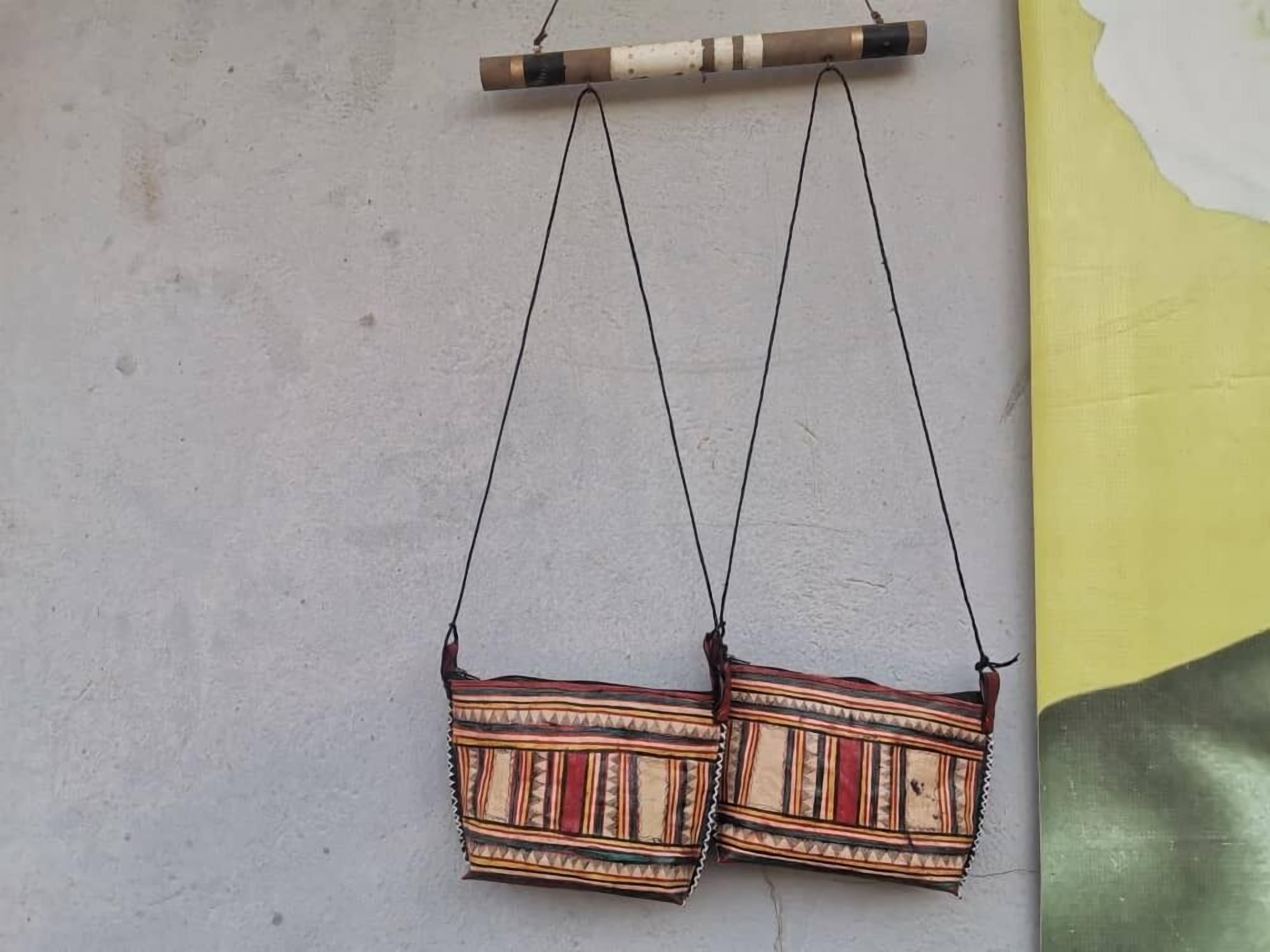 Two hanging bags with a patterned design against a plain wall.
