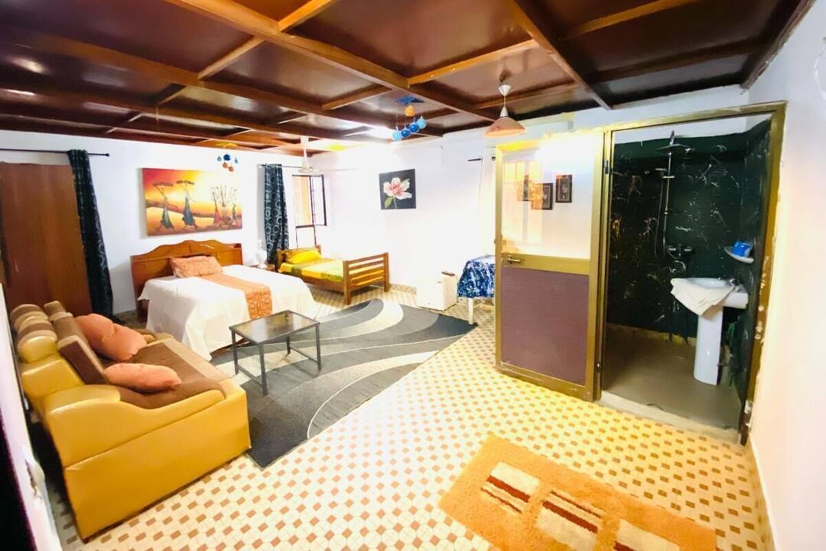 A hotel room with a bed, sofa, and a bathroom with a shower.