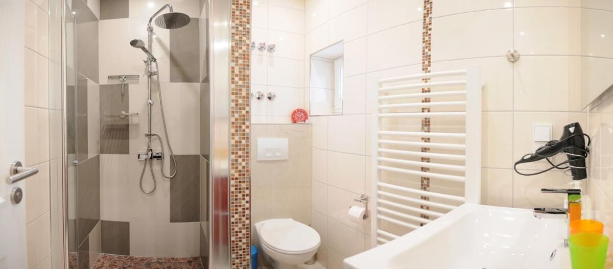 A bathroom with a glass shower enclosure, a white toilet, and a bathtub with a white towel rack.