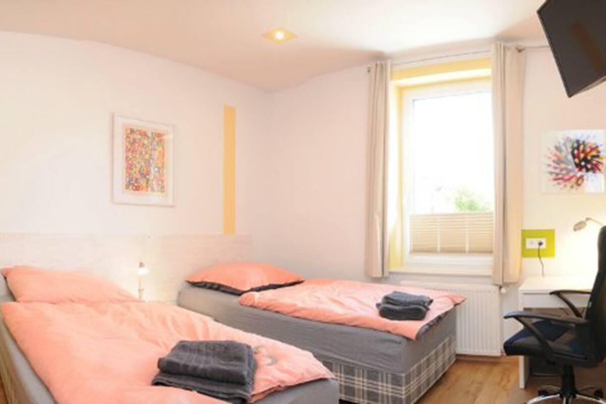A room with two beds, a desk, and a chair.