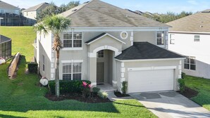 A single-story house with a garage, a front porch, and a small garden with a palm tree and shrubs. - Holiday Escape by VilllaDirect (Kissimmee)