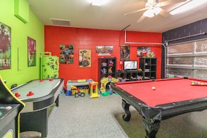 Une salle de jeux équipée d’une table de billard, d’un baby-foot et de divers jouets pour enfants.