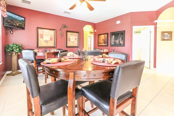 A dining room with a round wooden table, black chairs, and red walls.