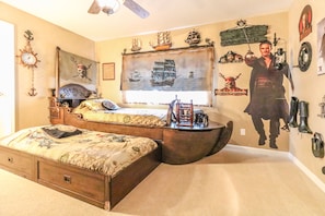 Une chambre à coucher avec un lit, une commode, une fenêtre et une fresque murale.