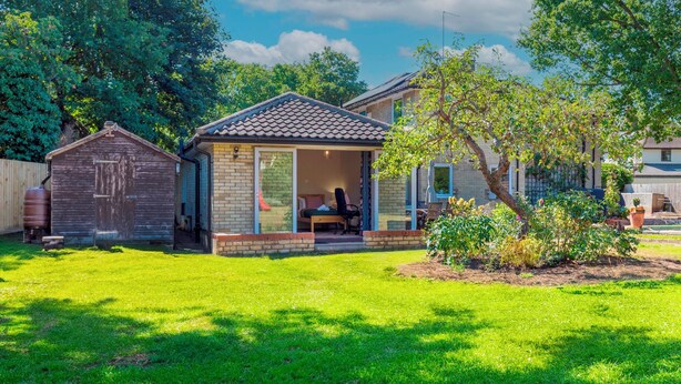 A residential house with a small attached garage, a covered patio, and a well-maintained lawn. - Pass the Keys | Charming and Central Garden Studio Flat | Free Parking (Cambridge)