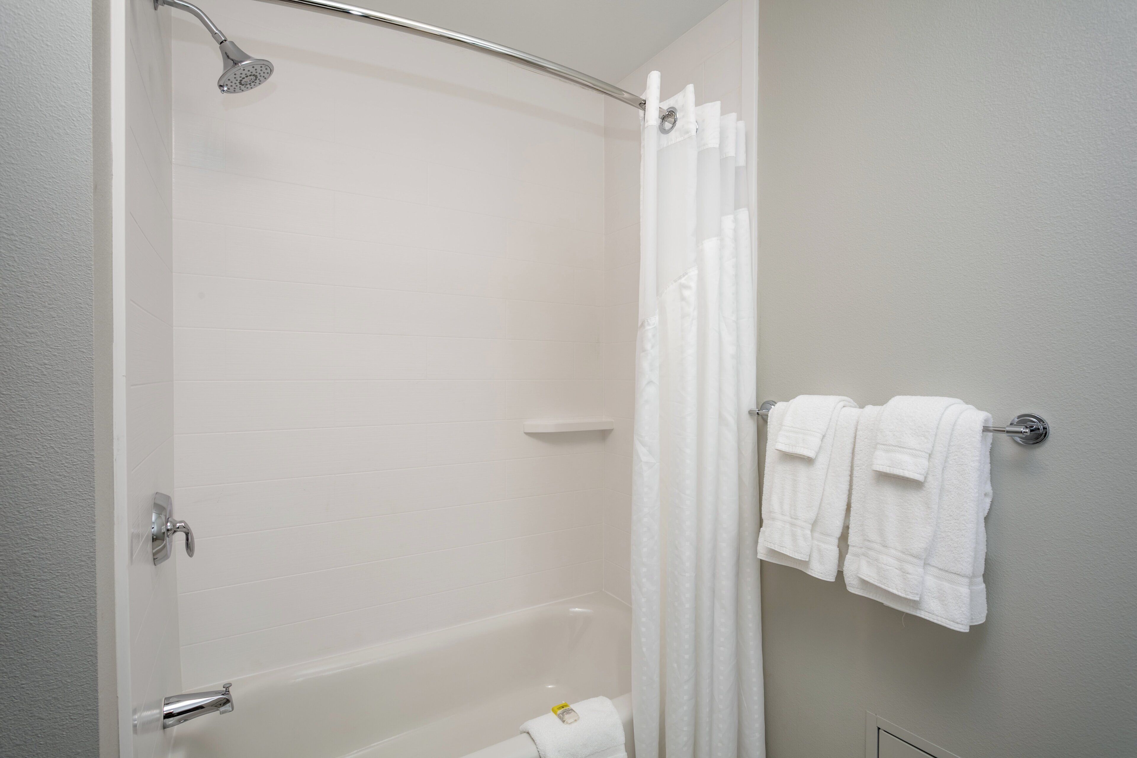 A bathroom with a bathtub, a shower, and a towel rack with towels.