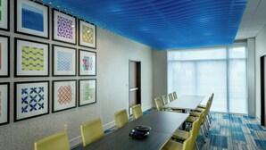 A conference room with a long table, yellow chairs, framed wall art, and a blue ceiling. - Holiday Inn Express & Suites Bend South by IHG (Bend)