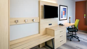 Camera d'albergo moderna con una scrivania in legno, una TV a schermo piatto, una tavolozza colori incorniciata e una sedia da ufficio verde.