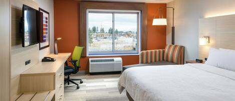 A hotel room with a bed, desk, chair, TV, and a window with a view.