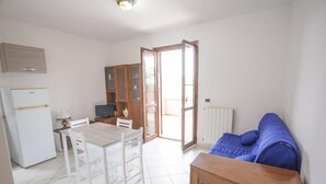 A compact living space with a dining area, kitchenette, and a sofa. - Bilocale Consumella (Portoferraio)