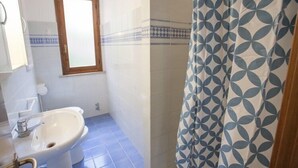 A bathroom with a sink, a window, and a shower curtain. - Bilocale Consumella (Portoferraio)