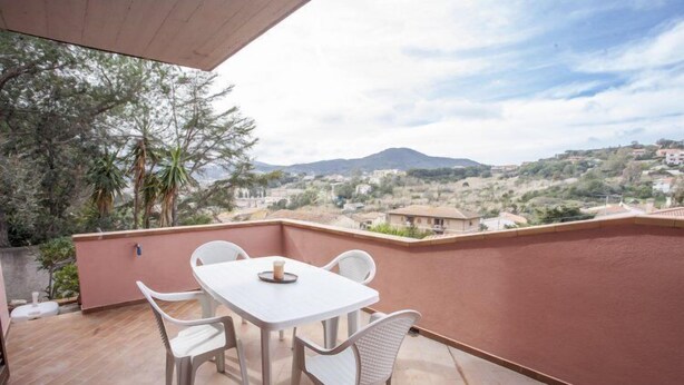 A patio with a table and chairs, overlooking a hilly landscape. - Bilocale Consumella (Portoferraio)