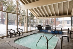 Una piscina interior con techo de madera y ventanas amplias.
