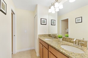 A bathroom with two sinks, a large mirror, and a ceiling light fixture.