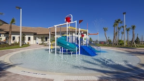 Ein Wasserpark mit einer blauen Rutsche, einem Wasserspielbereich und Palmen.