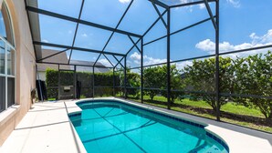 Piscina com água azul cristalina, rodeada por um revestimento de vidro e vista para o exterior.