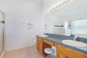 A modern bathroom with two sinks, a large mirror, and a shower area. - Haven Hideaway by VillaDirect (Davenport)