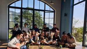 A group of people sitting on the floor in a room with large windows and wooden flooring. - Le Vent Homestay Tam Dao (Tam Dao)