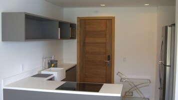Una cocina moderna con puerta de madera, encimeras blancas y un lavaplatos empotrado.