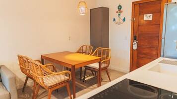 Un espacio habitable compacto con una mesa y sillas para comer, una kitchenette y una puerta de madera con pomo.