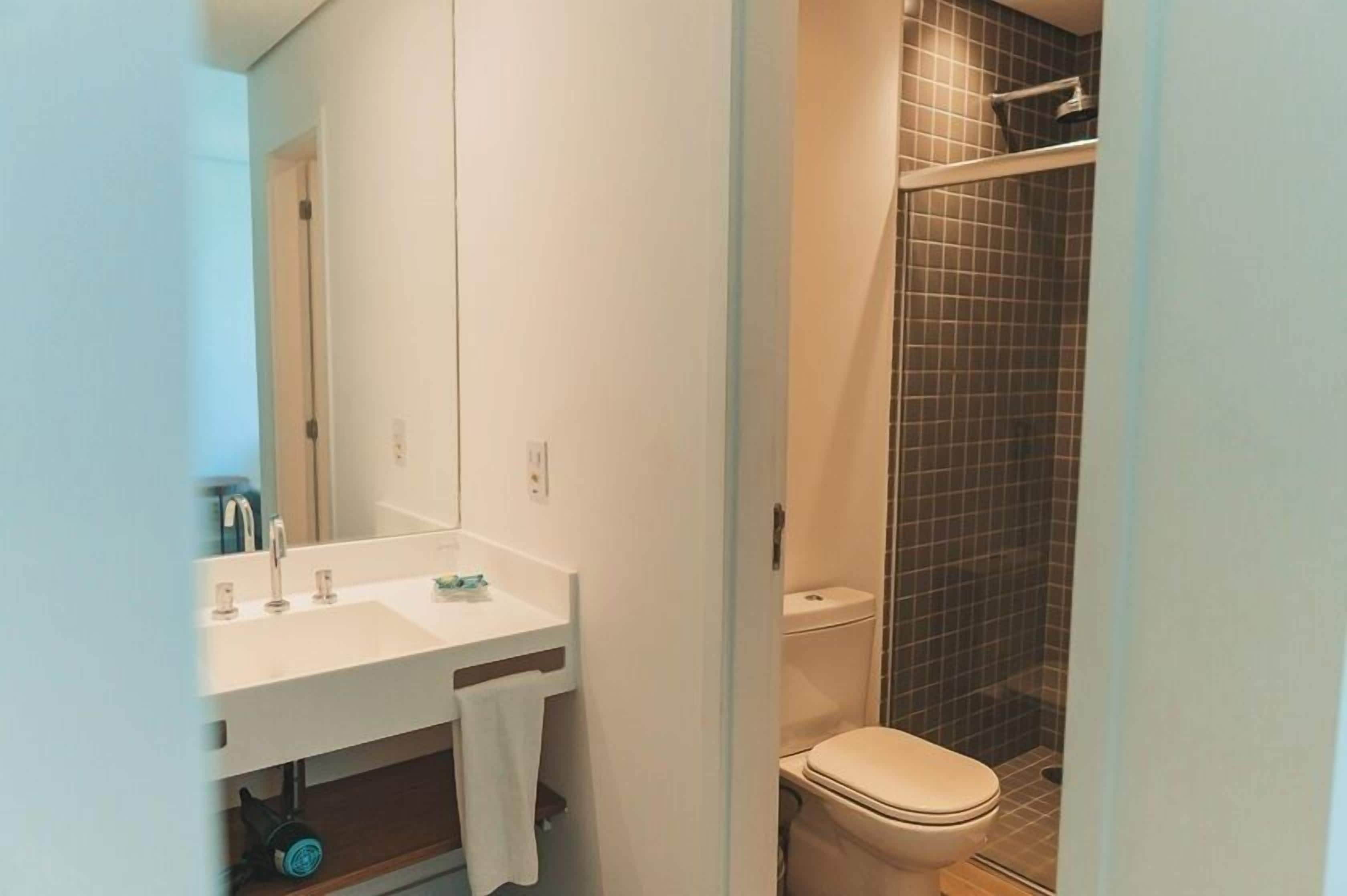 Un baño con lavamanos, espejo y retrete blancos.