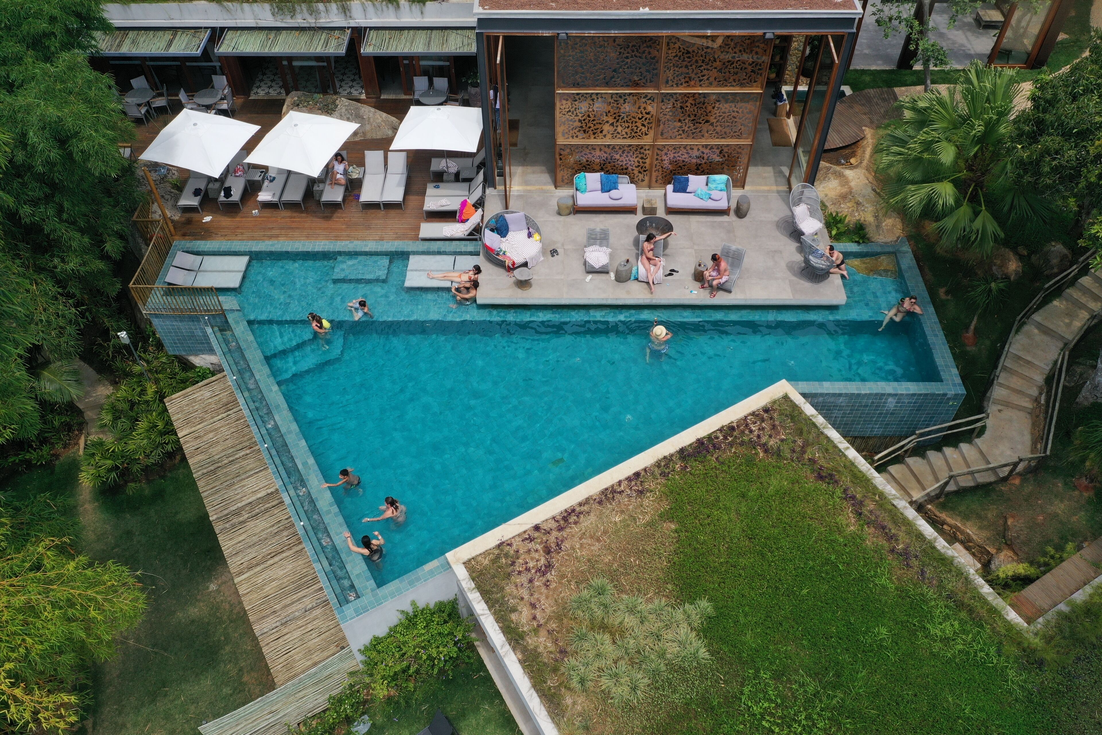 Vue aérienne d’un complexe hôtelier doté d’une piscine, d’espaces de détente et d’un espace de repos abrité.