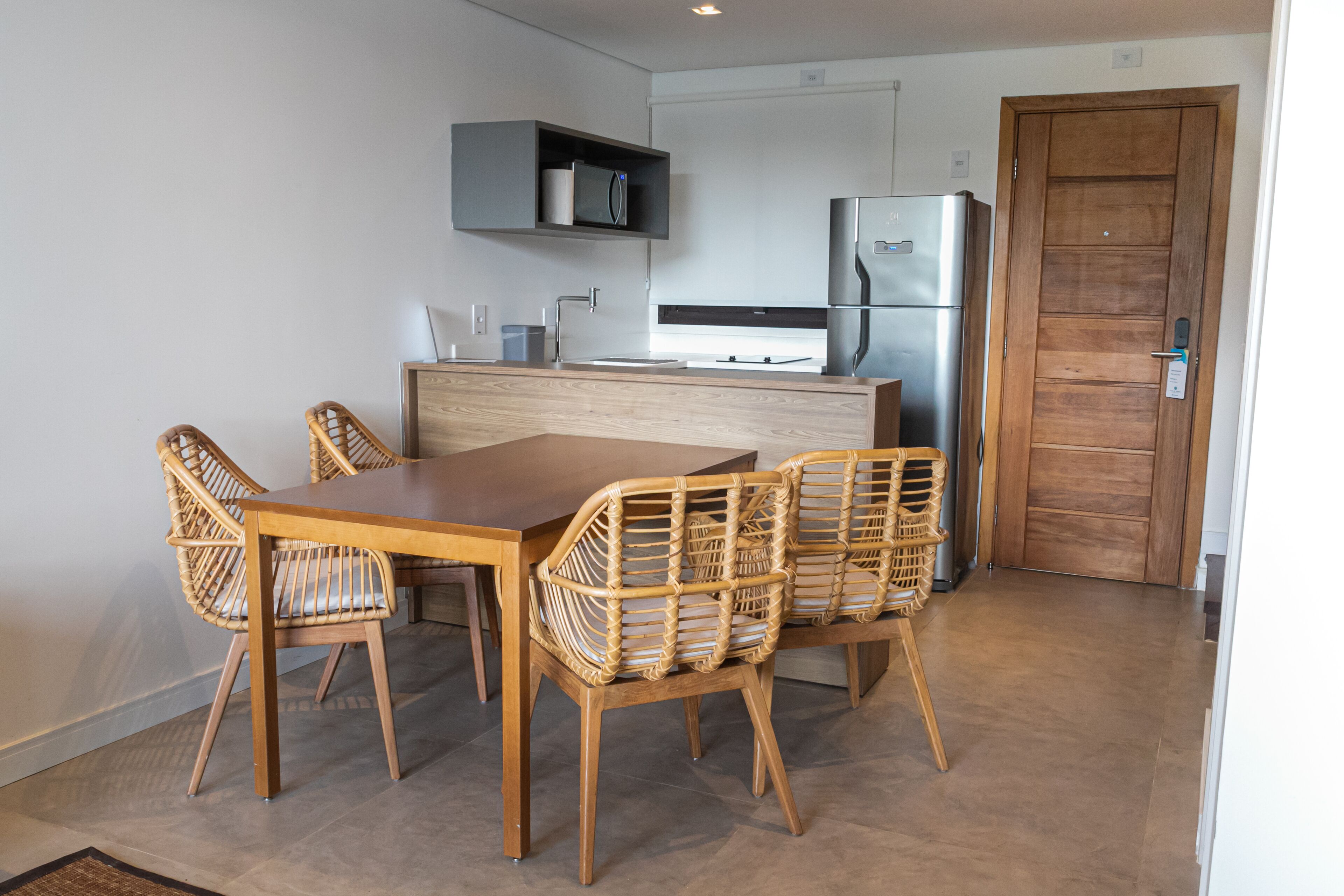 Een moderne keuken met een houten eettafel en stoelen, een ingebouwde magnetron en een koelkast.