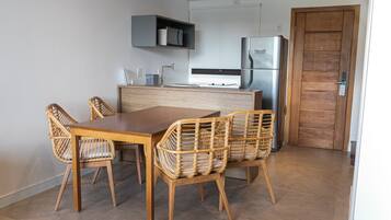 Een moderne keuken met een houten eettafel en stoelen, een ingebouwde magnetron en een koelkast.